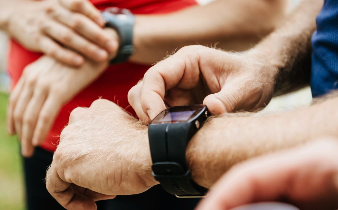 Sportowcy ustawiają swoje zegarki sportowe na nadgarstkach.