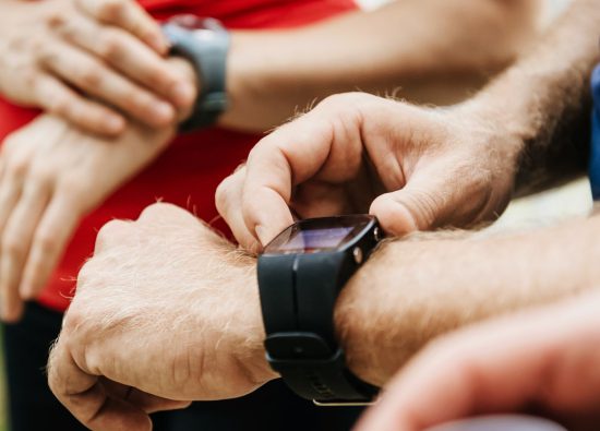 Sportowcy ustawiają swoje zegarki sportowe na nadgarstkach.