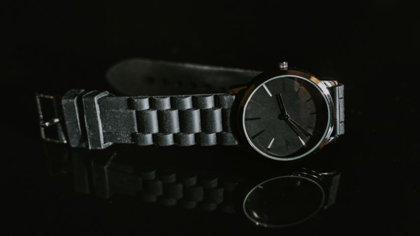 czarny mały zegarek męski na czarnym tle.