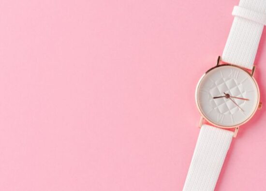 Typowy zegarek damski z gumowym, białym paskiem i małą tarczą na różowym tle.