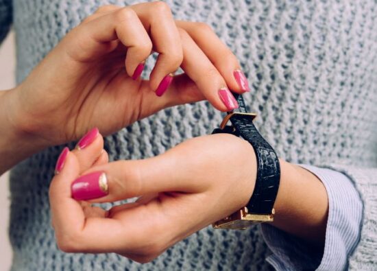 Kobieta zakłada zegarek damski na pasku na swój nadgarstek.