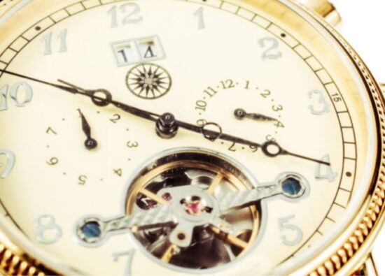 Złoty zegarek z widocznym mechanizmem w dolnej części tarczy.