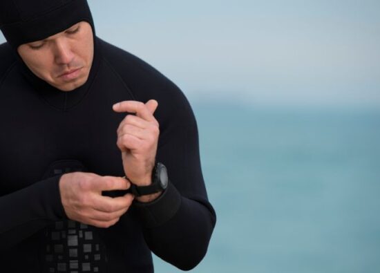 Mężczyzna w specjalnym stroju zakłada zegarek dla nurka.