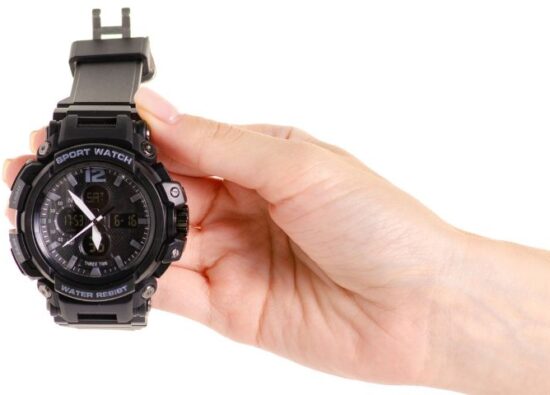 Kobieta prezentuje, jak wyglądają typowe zegarki G-shock. Na zdjęciu czarny zegarek tej marki.