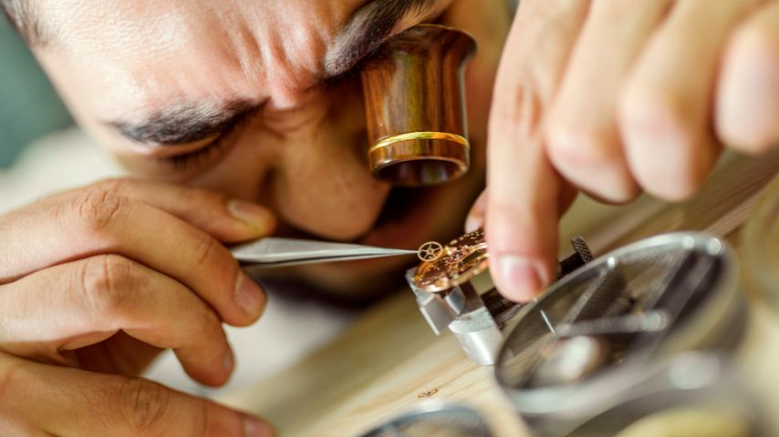 Zegarmistrz naprawia zniszczony zegarek za pomocą specjalnych narzędzi.